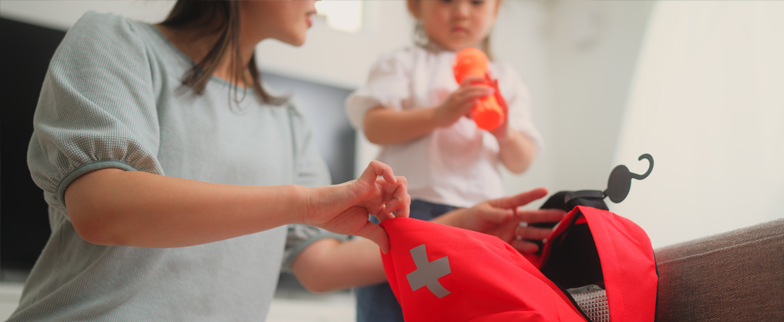 Parent putting items into a first aid bag with the help of their child.